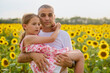 © czamfir - A man plays with his little girl in a sunflower field on a summer day.