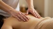 © PrabuanaAndika - Close-up of a massage therapist's hands gently kneading the back of a person on a massage table in a spa setting, showcasing relaxation and wellness.