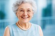 © Pixels Hunter - Happy senior woman with white hair and glasses smiling in soft natural light, wearing pearls against a modern blue blurred background.
