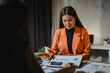 © PaeGAG - Two businesswomen are discussing over financial chart document late at night in the office