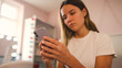 © Monkey Business - Close Up Of Teenage Girl Sitting On Bed At Home Looking At Mobile Phone