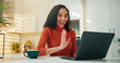 © peopleimages.com - Laptop, remote work and video call with woman in kitchen of home for greeting, hello or wave. Coffee, computer and virtual meeting with happy freelance employee in apartment for conference or webinar