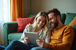 © Pete - Smiling couple enjoys tablet entertainment in cozy living room. Affectionate man and woman with beard and blonde hair relax together on sofa, using wireless technology for home entertainment.