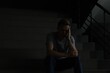 © New Africa - Sad man sitting on stairs in darkness. Depression