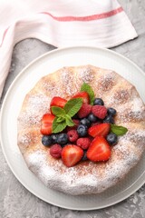 Wall Mural - tasty bundt cake with powdered sugar and berries on grey textured table, top view
