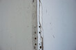 © Sasha - Cracks and peeling paint disturb the surface of a drywall corner, indicating wear in a residential living space