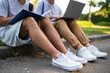 © zinkevych - Teens sitting on the pavement in the park and studying together