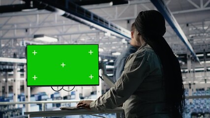 Software developer in server hub using chroma key workstation to scan equipment for issues. African american woman in data center uses isolated screen PC to do backups, camera B