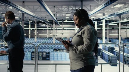 Server room tech support specialist guides clients through setting up secure company data backups. System administrator in data center helps users fix system errors on servers, camera A
