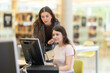 © JackF - In library, girl student uses public computer and listens to female friends advice, asks for help in assessing information. Student analyzes information on Internet, searches for information online