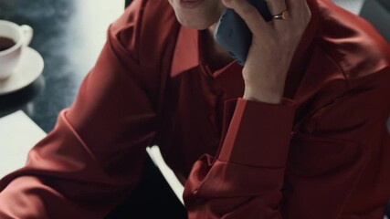 Wall Mural - Tilt down shot of middle-aged Caucasian female entrepreneur using laptop calling on mobile phone at office desk