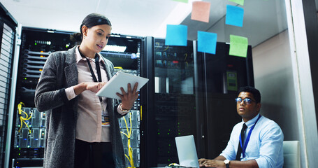 woman, tablet and talk with man in server room, programming or glass wall for it solution at company