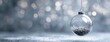 © abdul - Clear glass Christmas ornament with silver glitter, hanging against a soft, blurred backdrop of bokeh lights