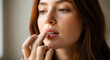 © Bangkit gultom - Close-up shot of a beautiful woman applying lip balm to her lips, enhancing her natural beauty with a touch of care and self-pampering.
