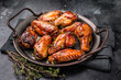 © Mironov - Savory grilled chicken wings smothered in tangy barbecue sauce, the ultimate treat for meat lovers and party enthusiasts. black background. top view