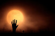 © Mind - Silhouetted hand reaches up against glowing moon in spooky graveyard scene
