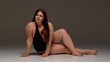 © Lustre Art Group  - A plus-size woman confidently poses in a black swimsuit, promoting body positivity and empowerment. Concept of embracing self-image and diversity in fashion.