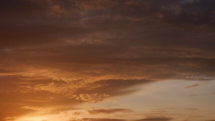 Wall Mural - a sunset time-lapse captures streaks of fiery orange and gold clouds layered against deep purples, a