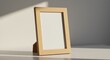 © Nur - Vertical blank wooden picture frame on a sunlit table.