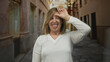 © Krakenimages.com - Caucasian middle age woman making loser sign on forehead in old town street; playful teasing mockery.