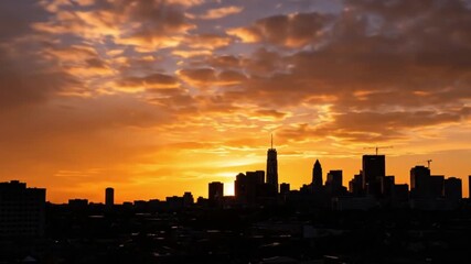 Wall Mural - A modern city skyline silhouetted against a dramatic and colorful sunset with vibrant orange clouds.