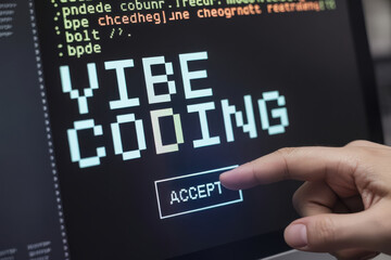 Coding concept is shown by touching a computer screen with VIBE CODING text on it, with the word ACCEPT below the text