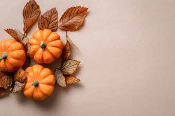Poster - Orange pumpkins and autumn leaves on beige background