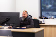 © Austockphoto - Business owner seated at desk in office indoors smiling at computer screen