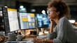 © Korawan - A woman is sitting at a desk with two computer monitors in front of her