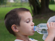© light - Concept of thirst and refreshment. A boy's face is seen in profile as he drinks from a bottle to hydrate himself.