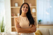 © Dexon Dee - Smiling woman standing indoors with arms crossed, looking confident and approachable in a modern bright home interior.