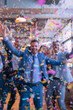 © Ilia - Blurred background of people in business suits celebrating in an office, throwing confetti and holding party streamers. Concept of corporate celebration, team success, and joyful workplace moments.
