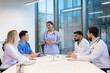 © Liubomir - Medical professionals engaging in a collaborative discussion around a table in a modern office environment, showcasing communication, teamwork, and professional exchange.