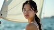 © Olga - Attractive Asian girl on a yacht, with a sail in the background on a summer day