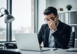 © PP Creative - A stressed businessman rubs his eyes while working late on his laptop in a modern office, feeling overwhelmed and exhausted from his demanding job