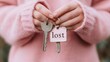 © Margarita Ratatosk - Woman holding lost house keys, concept of losing possession or moving. Pink sweater and broken keys with tag.