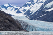© AJCalPhotos - A stunning view of Alaska's Surprise Glacier. The massive blue and white ice field flows between two rugged, snow-capped mountains and calves into the water below, filled with floating ice.