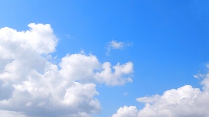Wall Mural - Clear blue sky with white clouds. Panoramic blue sky background with fluffy white cumulus clouds. Aerial view of cloudscape on sunny day.