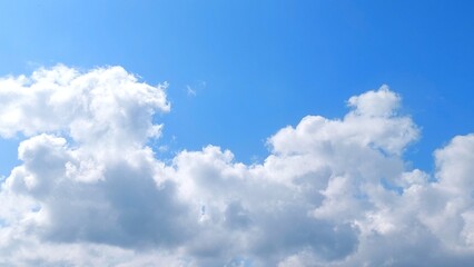 Wall Mural - Clear blue sky with white clouds. Panoramic blue sky background with fluffy white cumulus clouds. Aerial view of cloudscape on sunny day.