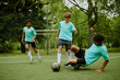 © Seventyfour - Three teenage boys playing soccer on outdoor field, one Black teenager sliding to tackle ball while others running and focusing on game action
