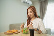 © WMSTUDIO - Woman Enjoying a Healthy Salad Next to a Pizza with a Glass of Soft Drink in Modern Bright Interior Full of Natural Light