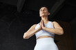 © DragonImages - Portrait of senior Caucasian woman practicing yoga, standing with eyes closed and hands pressed together in prayer position, wearing sportswear, focusing on mindfulness