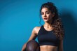 © TuruMuru - Attractive Indian woman in black athletic gear holding a football against a blue backdrop