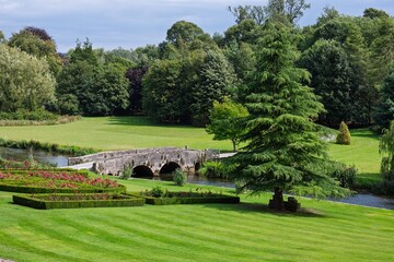Wall Mural - scenic view of a stone bridge in a lush, green impressive country house garden peak district.