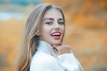 Wall Mural - Autumn portrait of happy young woman. Smiling woman on autumn fall background. Beauty girl with fall leaves. Autumn model with fall maple leaf. Autumn portrait of beautiful happy girl.