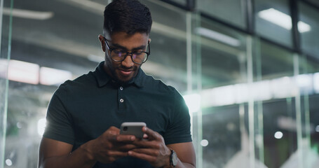 Business, phone and reading with man in office at night for creative update or design deadline. App, communication and typing with designer in workplace for evening research or mobile text message