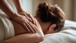© ZHAOQINGHUA - Close-up hands massaging back of person on towel, soft light therapy