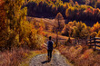 © astrosystem - Woman hiking on a countryside dirt road in autumn season.