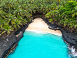 © Curioso.Photography - Tropical aerial view of Battery Beach on Rolas Island, São Tomé and Príncipe, showcasing turquoise water, black volcanic rocks, and dense green palm forest.