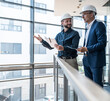 © BusinessClass by W61 - Engineers discussing project indoors at modern office in safety helmets
